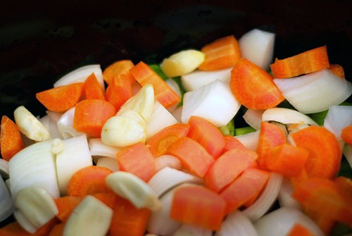 Carrots, celery, onion, and garlic sitting in a slow cooker for the beef bone broth recipe.