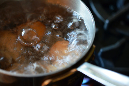 Water boiling in a saucepan with eggs inside.