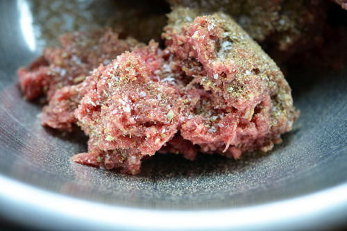 Ground beef in a metal bowl with Tabil seasoning on top.