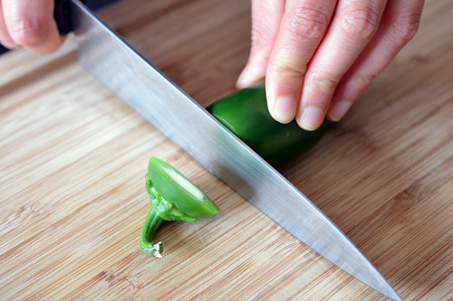 Someone chopping off the end of a jalapeño.