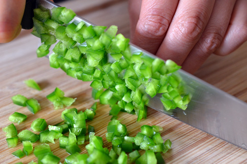 Someone finely dicing the jalapeño for spicy pineapple salsa.