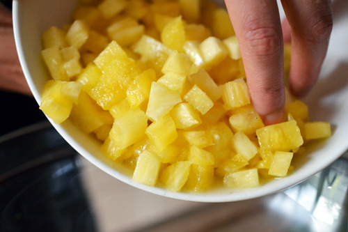 Someone pouring the diced pineapple into a bowl for spicy pineapple salsa.