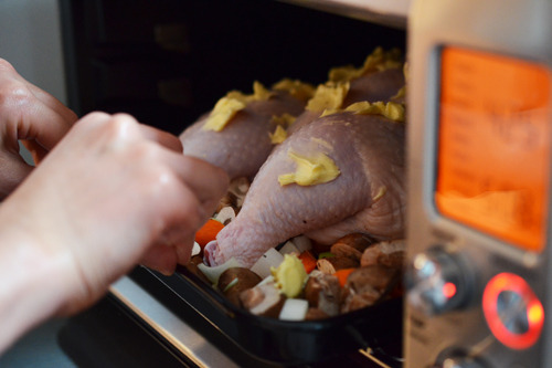 Someone placing a tray of the easiest roast chicken ever into a toaster oven to cook.