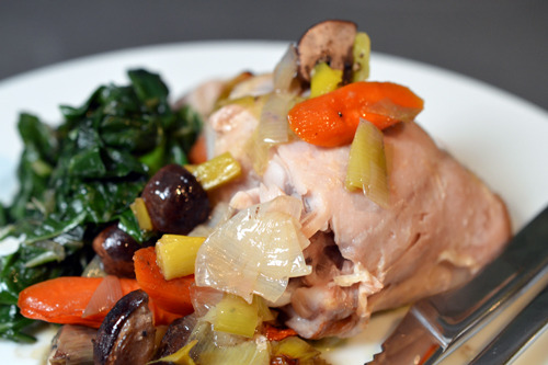 Easiest roast chicken ever on a plate with sautéed spinach and vegetables.
