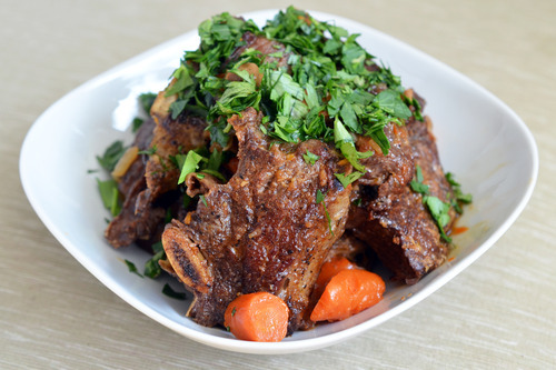A bowl of porcini and tomato beef short rib topped with parsley.