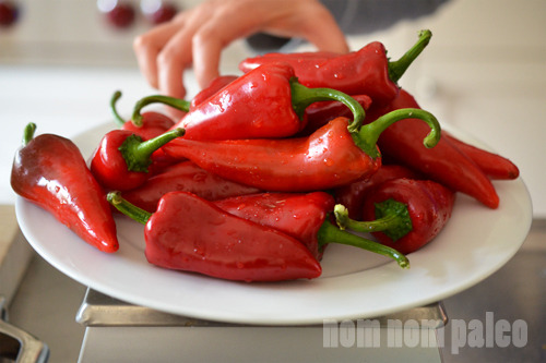 A plate filled with red jalapeño peppers on a kitchen scale.